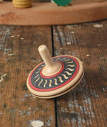 Mader Kreiselmanufaktur arabesk wooden finger spinning top placed on a wooden desk in the Babipur playroom.
