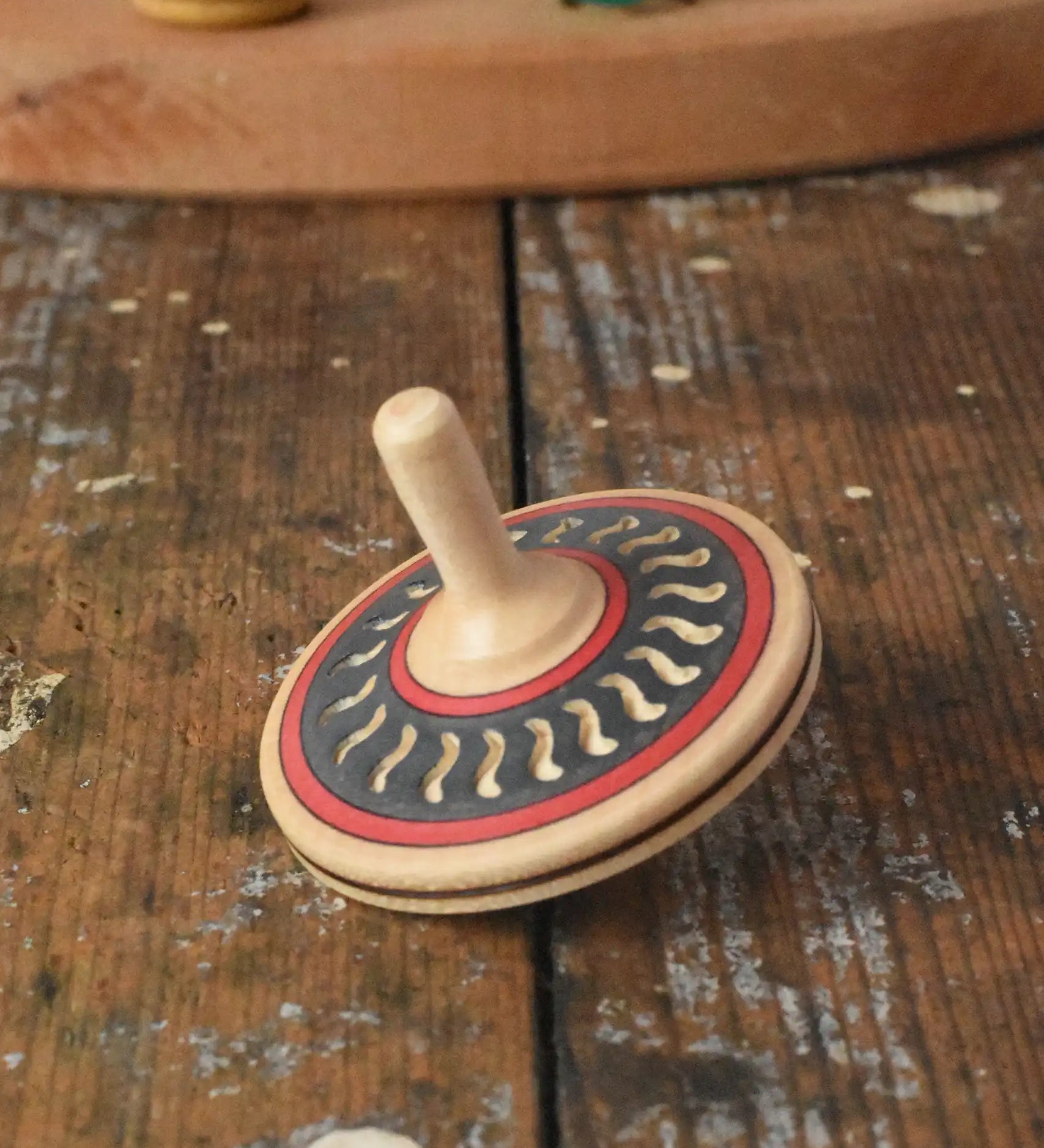 Mader Kreiselmanufaktur arabesk wooden finger spinning top placed on a wooden desk in the Babipur playroom.