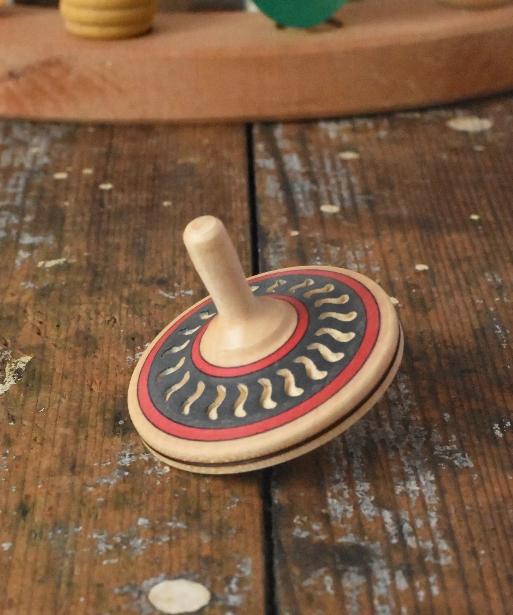 Mader Kreiselmanufaktur arabesk wooden finger spinning top placed on a wooden desk in the Babipur playroom.