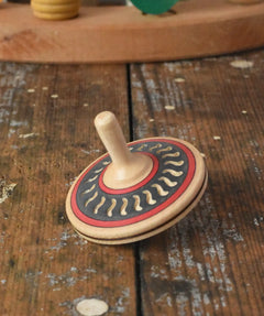 Mader Kreiselmanufaktur arabesk wooden finger spinning top placed on a wooden desk in the Babipur playroom.