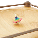 Close up of a Mader Rainbow stripe spinning toy on a Mader large wooden spinning plate