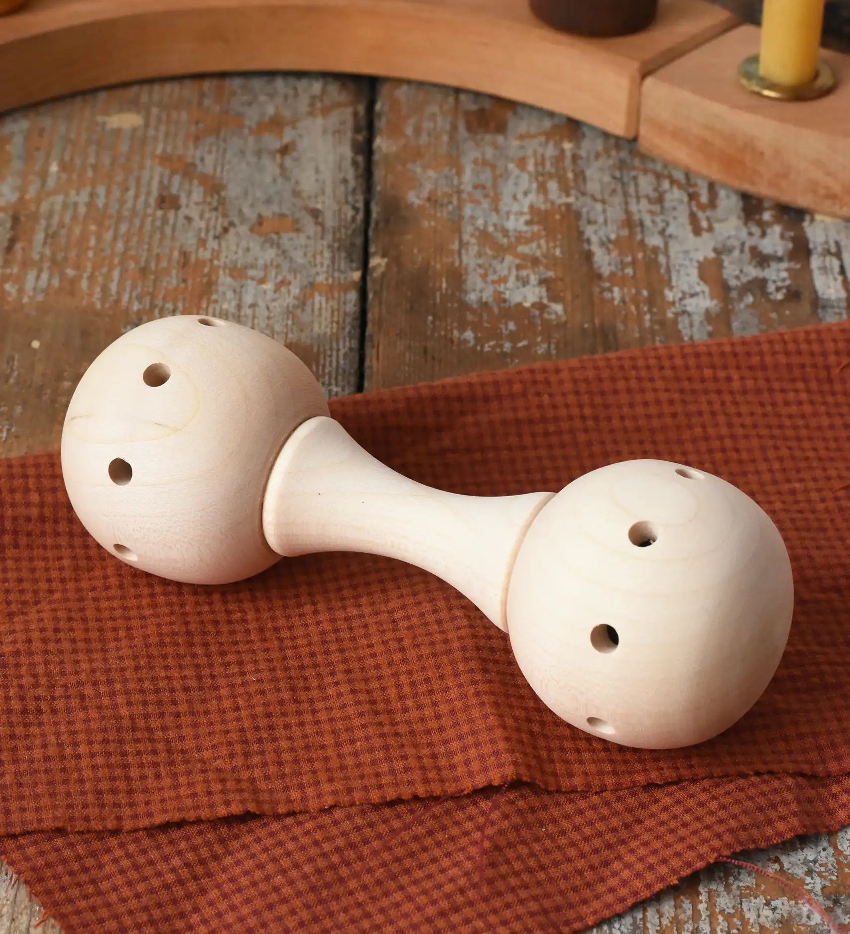 Mader Kreiselmanufaktur traditional wooden baby rattle placed on a cloth on a wooden surface in the Babipur playroom. 
