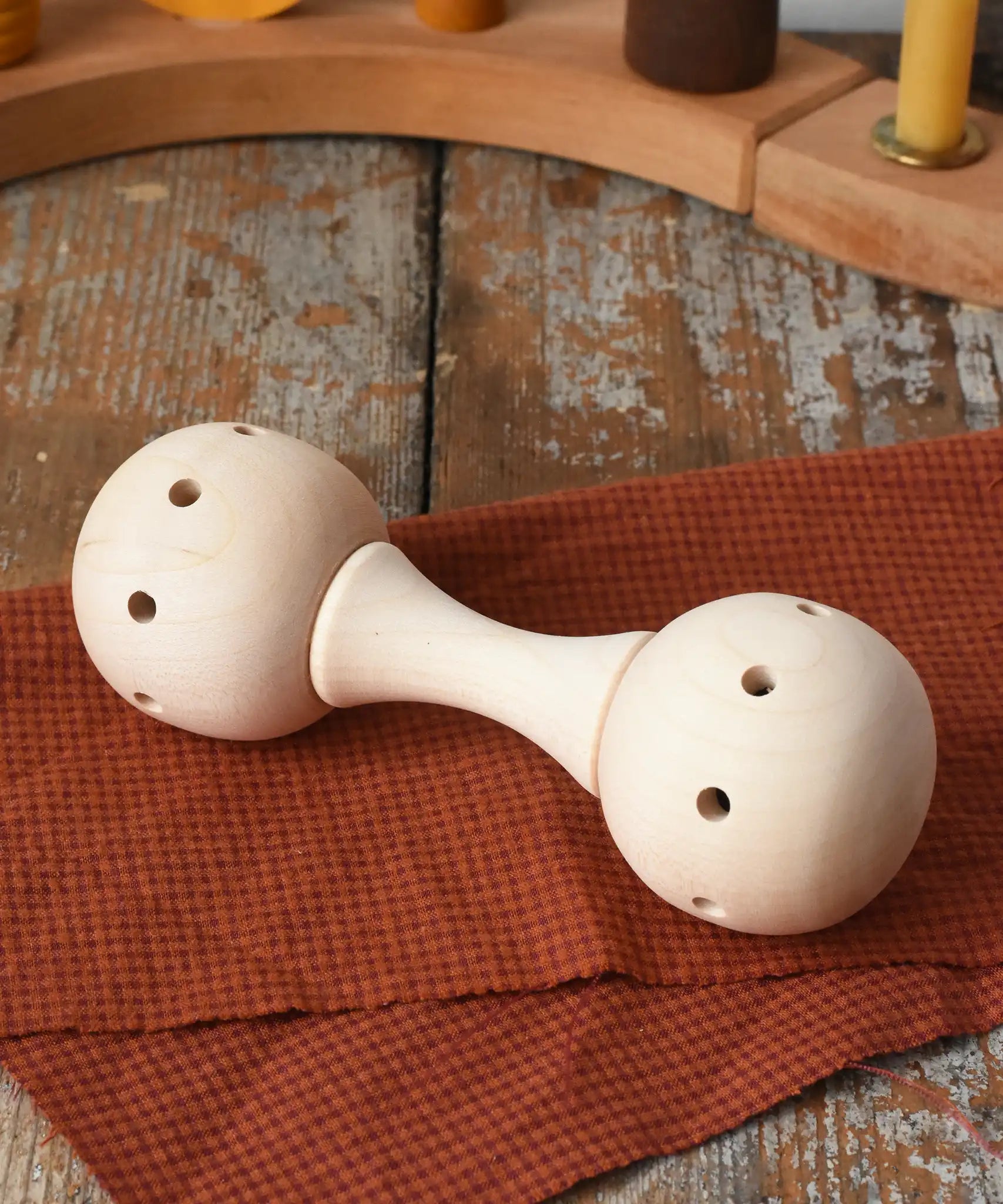 Mader Kreiselmanufaktur traditional wooden baby rattle placed on a cloth on a wooden surface in the Babipur playroom. 