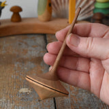 Mader Ballerina wooden spinning top in an adult's hand in the Babipur playroom. 