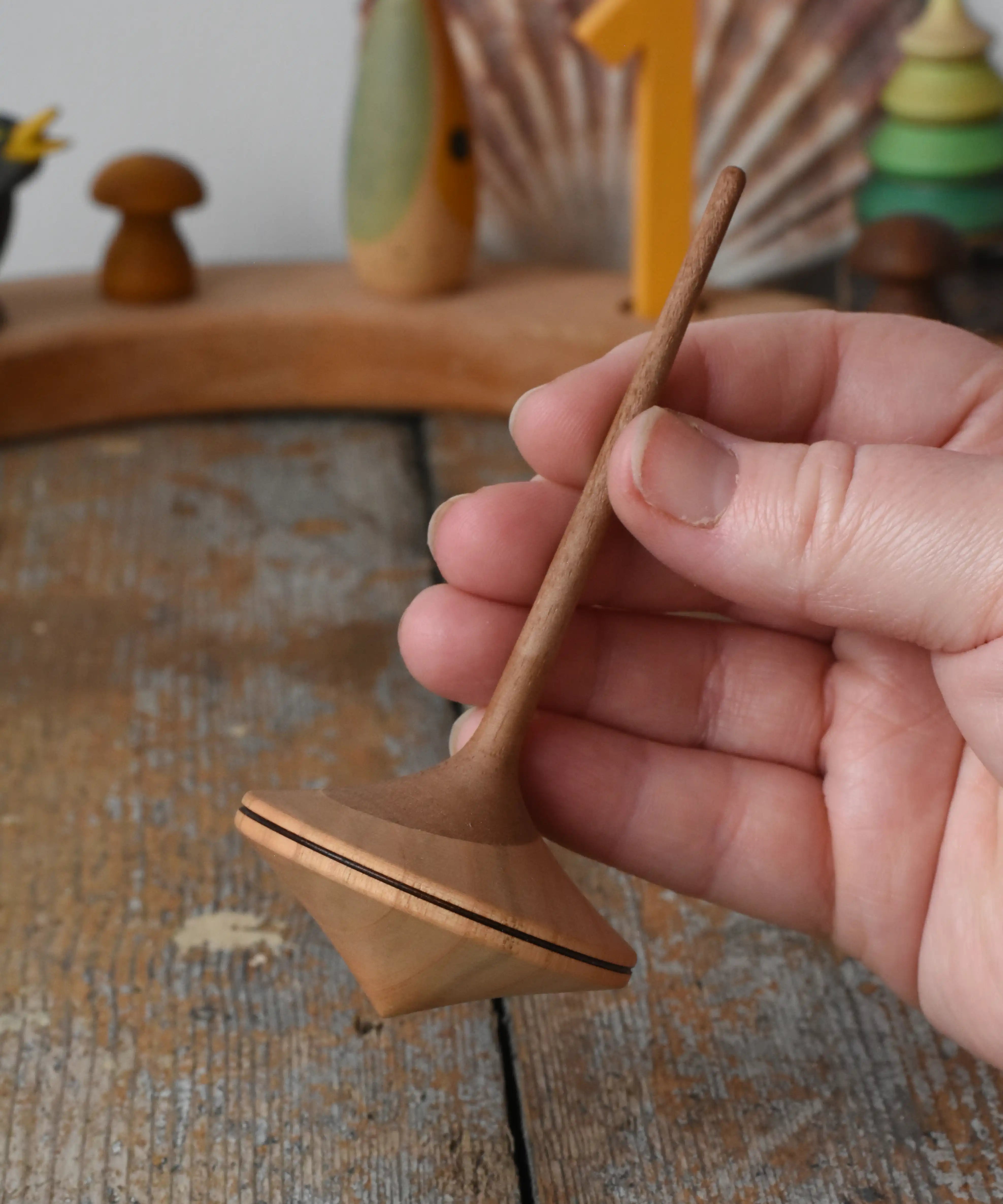 Mader Ballerina wooden spinning top in an adult's hand in the Babipur playroom. 