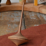 Mader ballerina wooden spinning top  placed on a piece of cloth on a wooden surface in the Babipur playroom. 