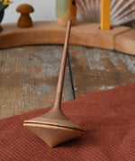 Mader ballerina wooden spinning top  placed on a piece of cloth on a wooden surface in the Babipur playroom. 