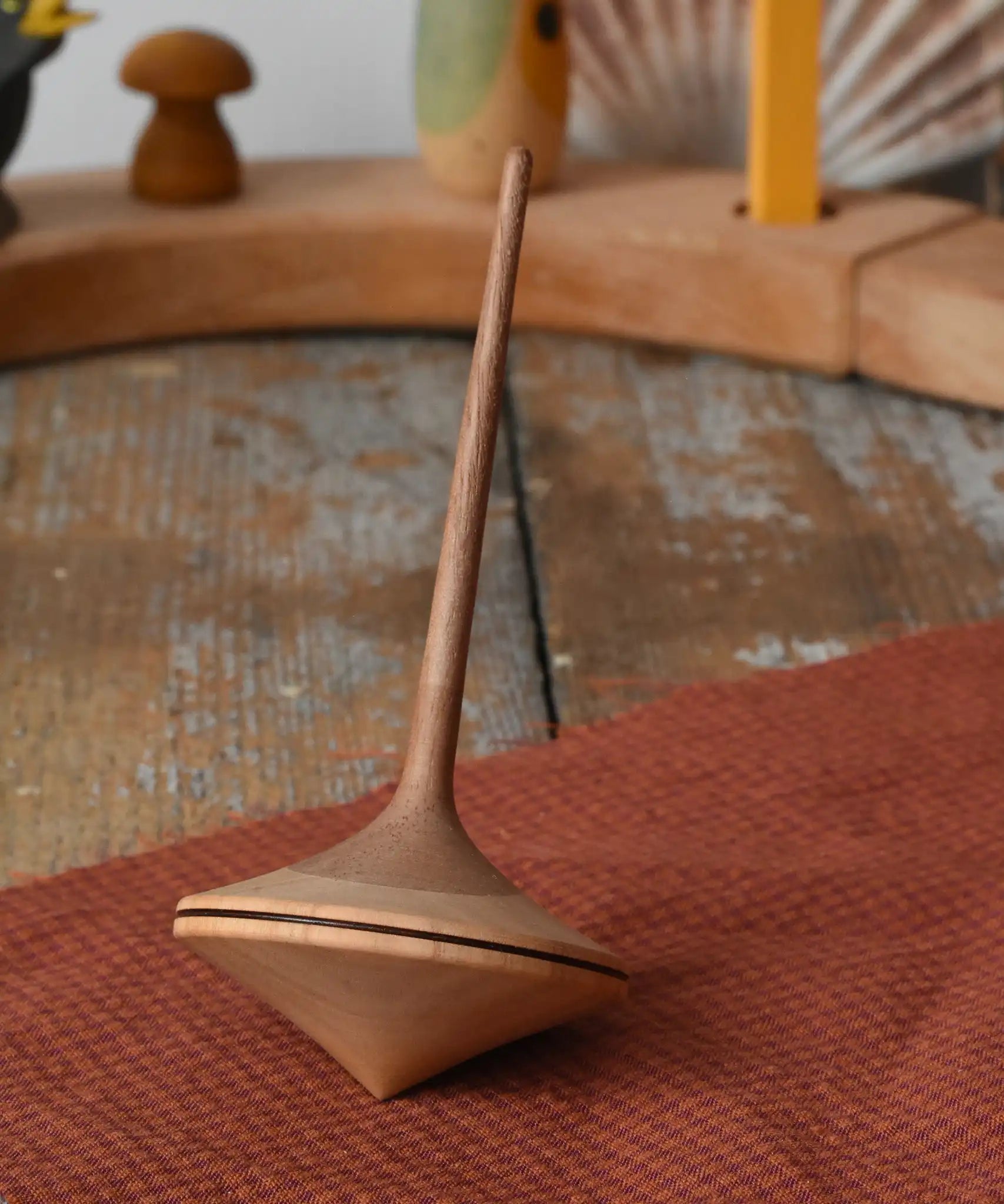Mader ballerina wooden spinning top  placed on a piece of cloth on a wooden surface in the Babipur playroom. 