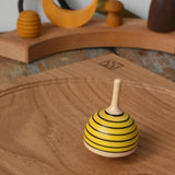 Mader bee spinning top spinning in motion on on oak plate in the Babipur playroom. 