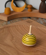 Mader bee spinning top spinning in motion on on oak plate in the Babipur playroom. 