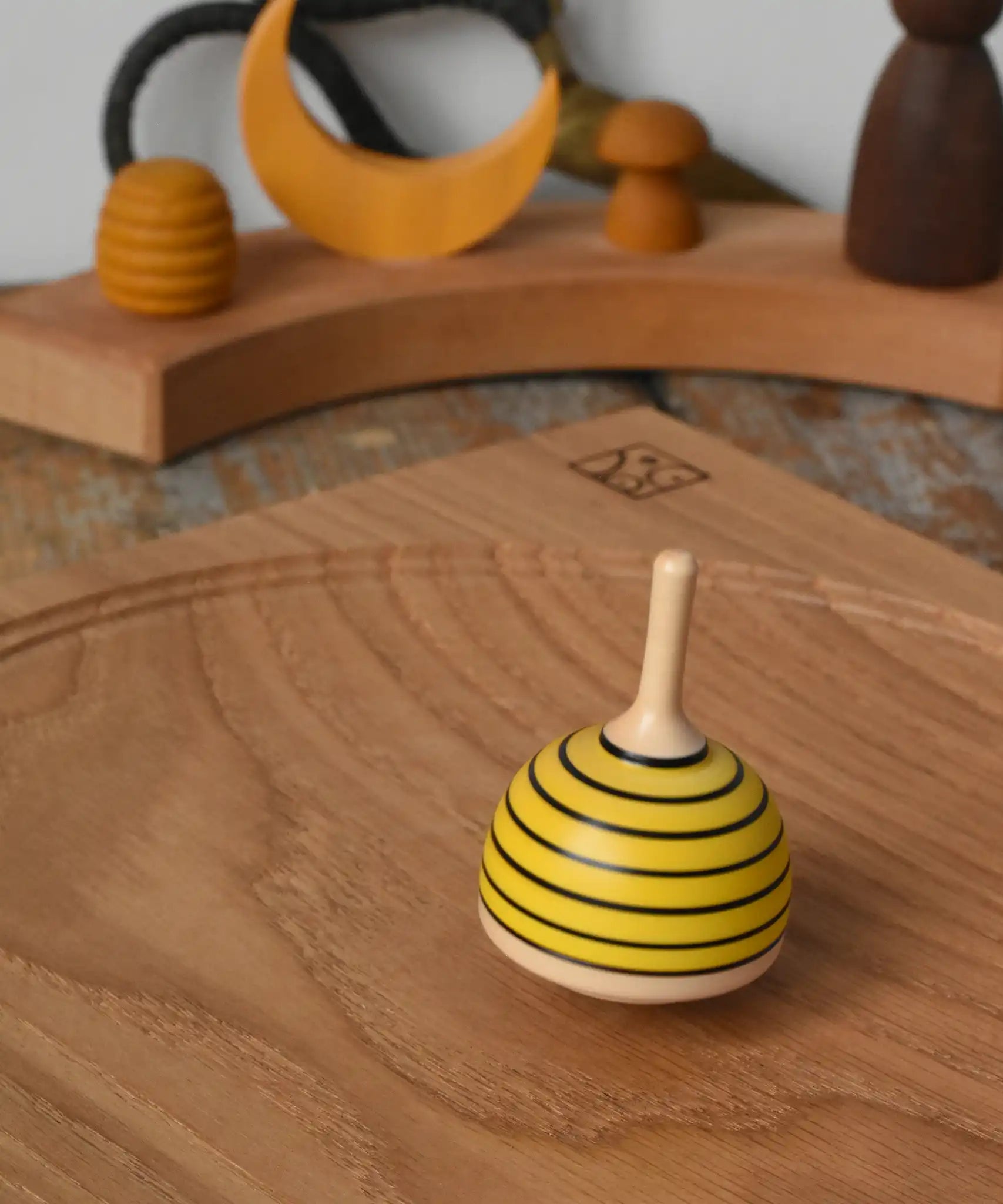 Mader bee spinning top spinning in motion on on oak plate in the Babipur playroom. 