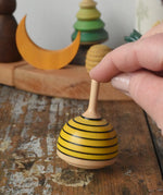 Mader bee spinning top placed on a wooden desk in the Babipur playroom. 