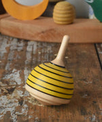 Mader bee spinning top placed on a wooden desk in the Babipur playroom. 