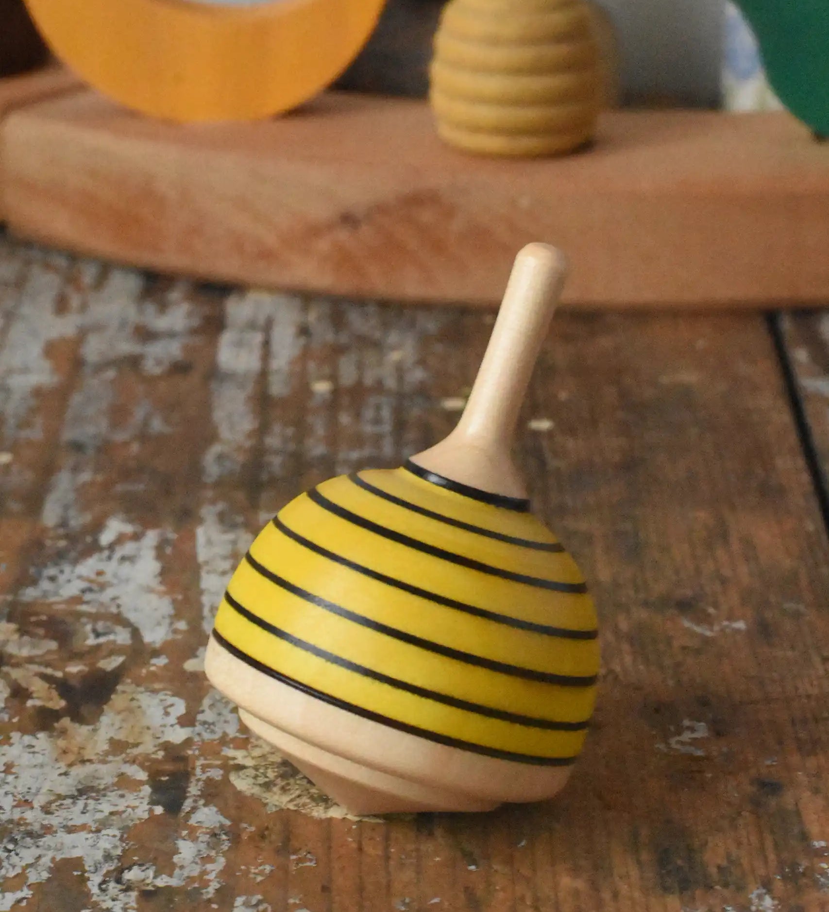 Mader bee spinning top placed on a wooden desk in the Babipur playroom. 
