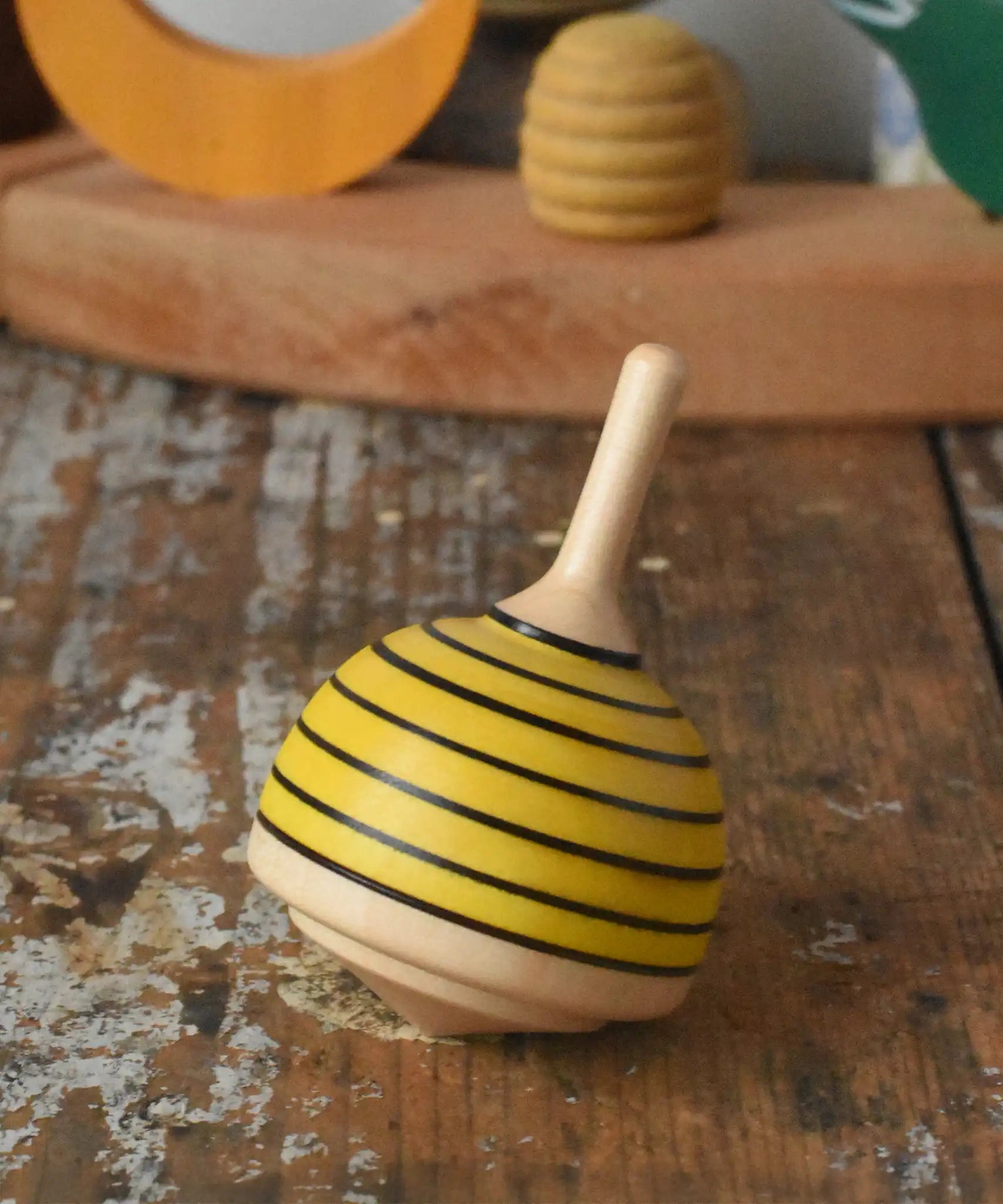 Mader bee spinning top placed on a wooden desk in the Babipur playroom. 