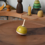 Mader bee spinning top spinning in motion on a walnut plate in the Babipur playroom. 