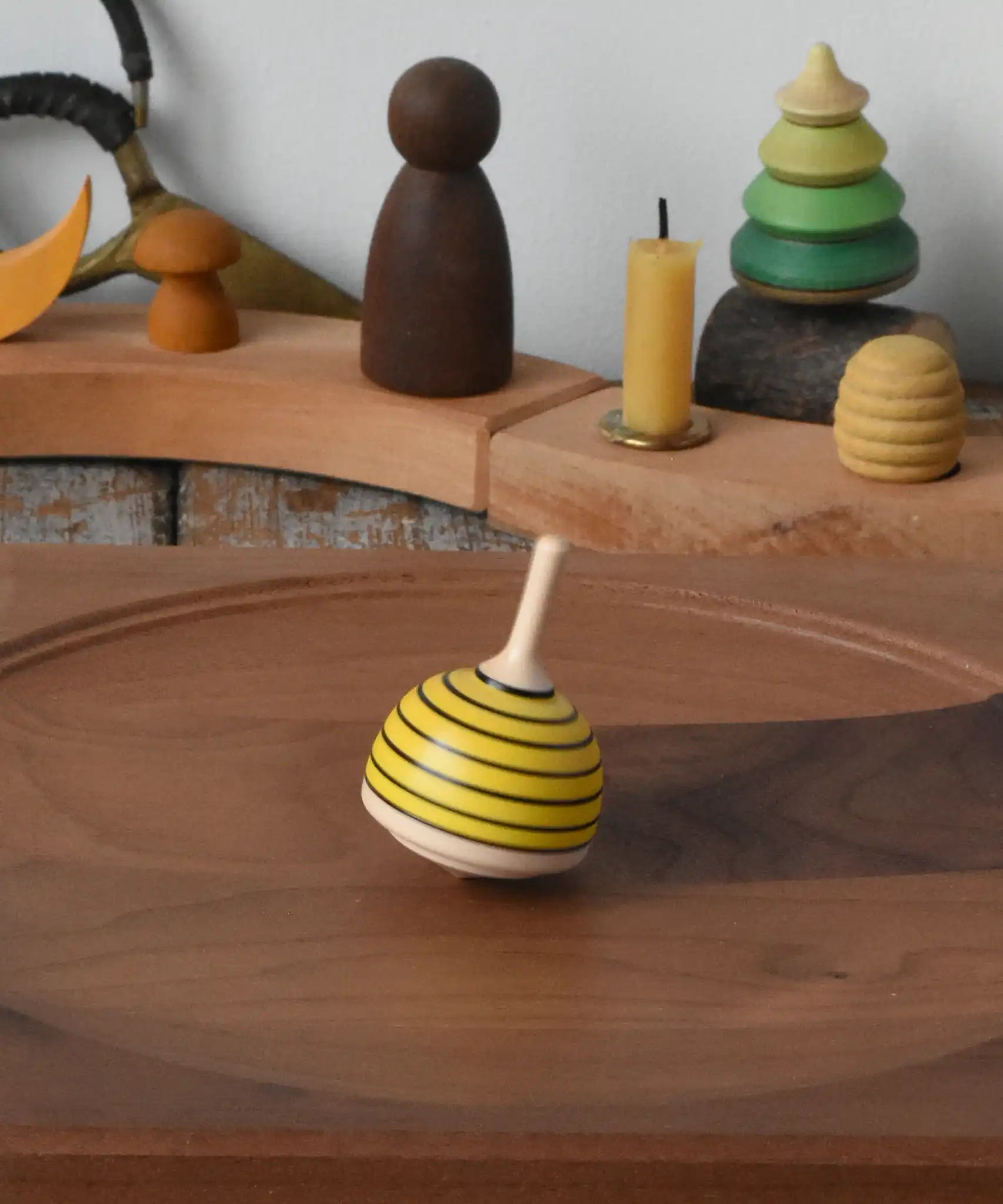 Mader bee spinning top spinning in motion on a walnut plate in the Babipur playroom. 