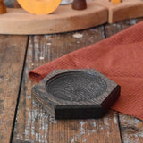 Mader hexagon 8cm spinning top plate in black oak placed on a wooden surface in the Babipur playroom.