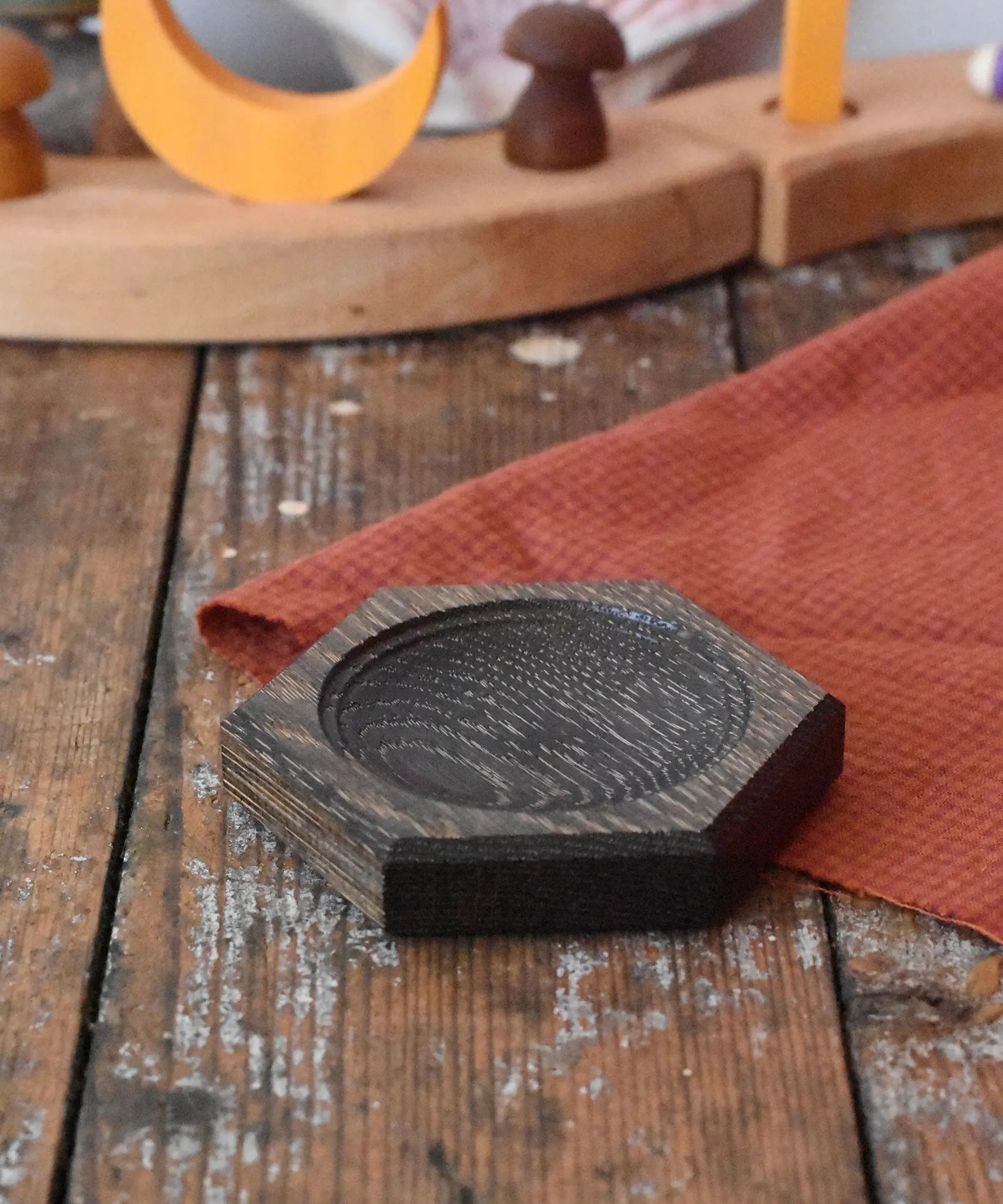 Mader hexagon 8cm spinning top plate in black oak placed on a wooden surface in the Babipur playroom.