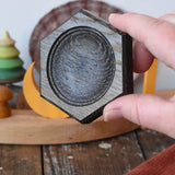 Mader hexagon 8cm spinning top plate in black oak in an adult's hand