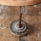 Black Mader Kreiselmanufaktur bonbon wooden spinning top placed on a wooden desk in the Babipur playroom.