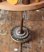 Black Mader Kreiselmanufaktur bonbon wooden spinning top placed on a wooden desk in the Babipur playroom.