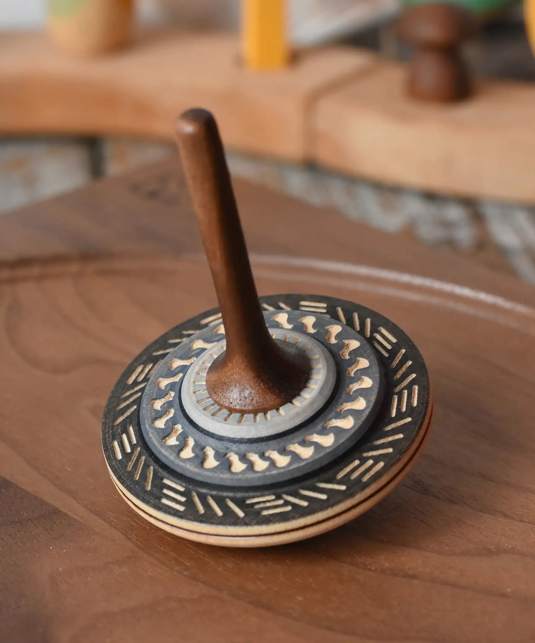 Mader Kreiselmanufaktur bonbon wooden spinning top in black placed on a walnut wood spinning plate in the Babipur playroom.