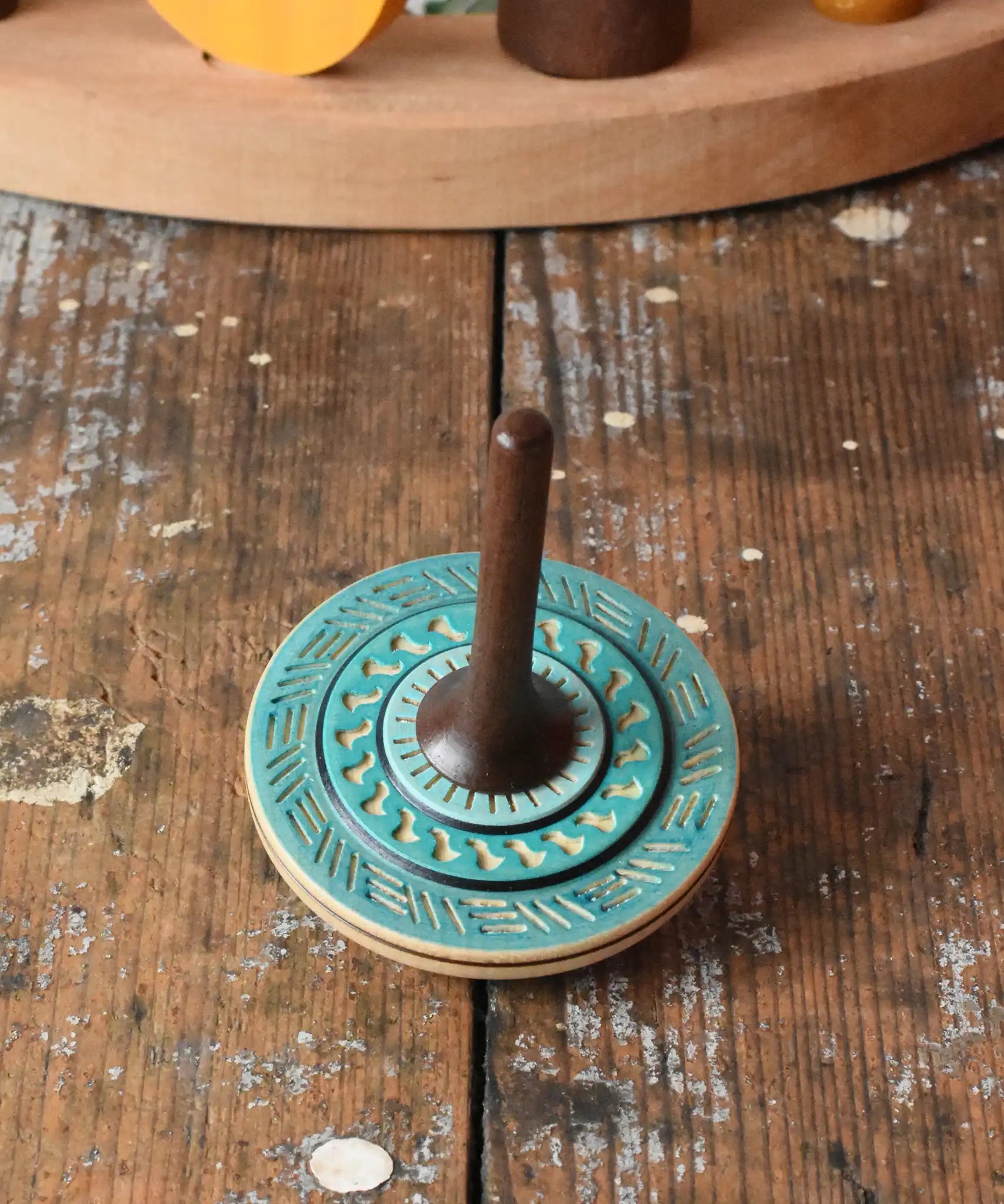 Blue Mader Kreiselmanufaktur bonbon wooden spinning top placed on a wooden desk in the Babipur playroom.