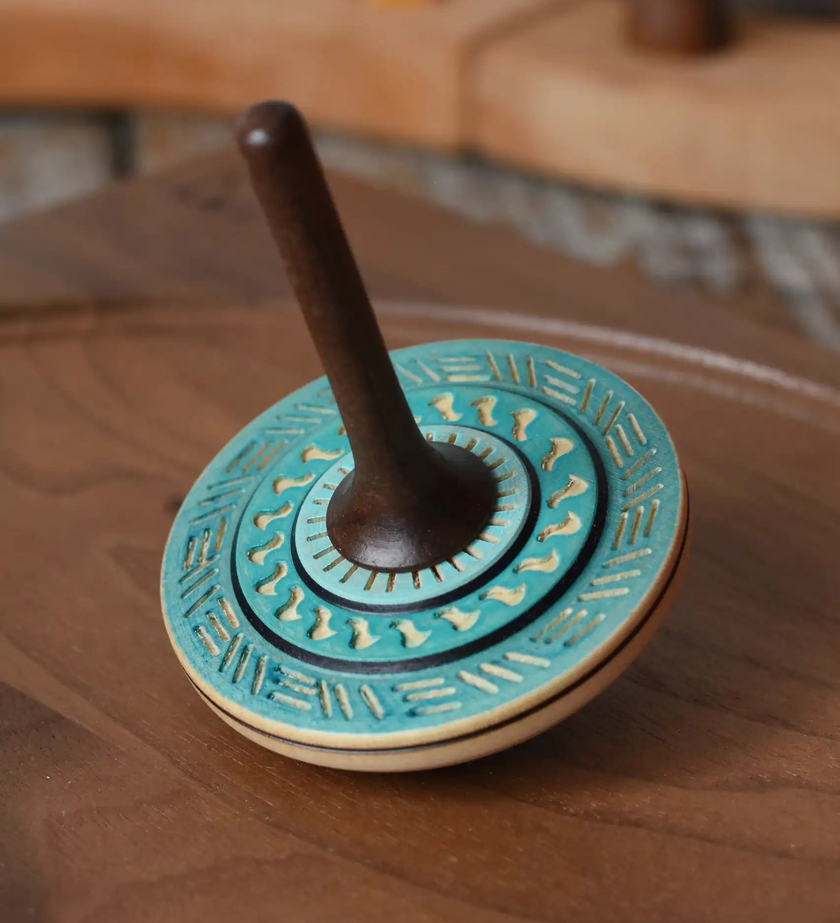 Mader Kreiselmanufaktur bonbon wooden spinning top in blue placed on a walnut wood spinning plate in the Babipur playroom.