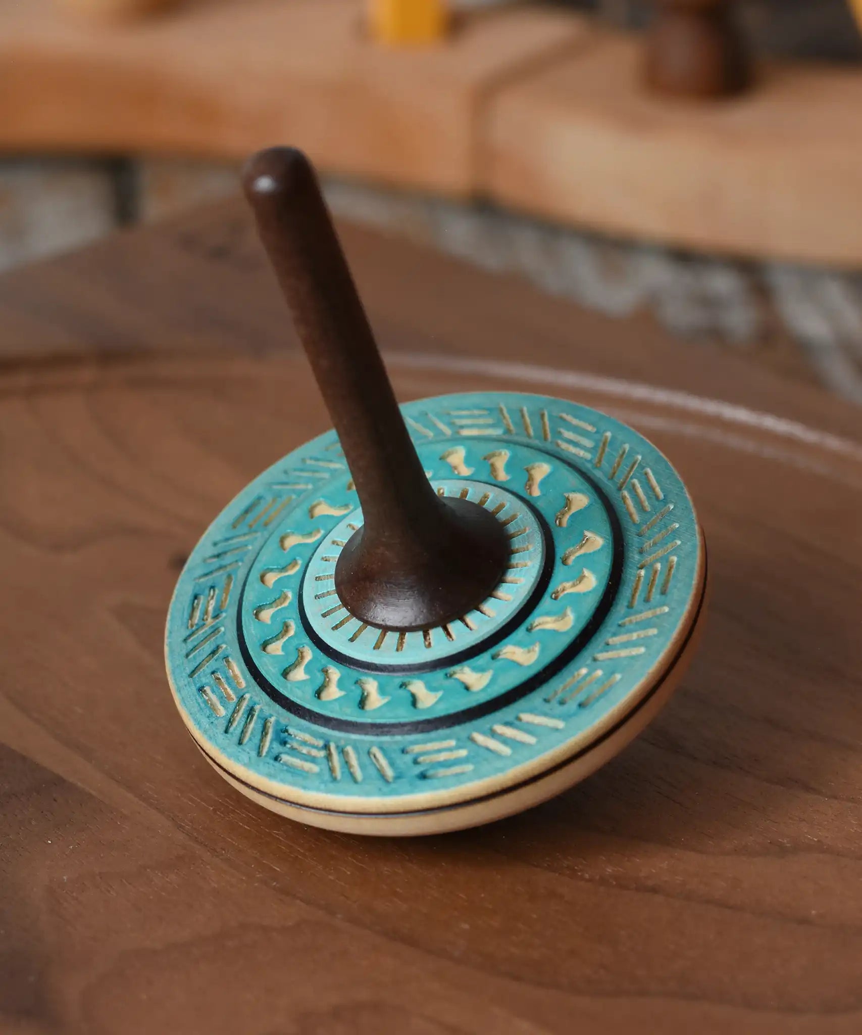 Mader Kreiselmanufaktur bonbon wooden spinning top in blue placed on a walnut wood spinning plate in the Babipur playroom.