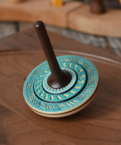 Mader Kreiselmanufaktur bonbon wooden spinning top in blue placed on a walnut wood spinning plate in the Babipur playroom.