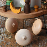 Bottom of three Mader Kreiselmanufaktur bonbon wooden spinning tops placed on a wooden desk in the Babipur playroom.