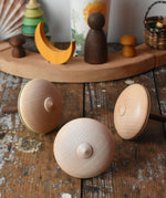 Bottom of three Mader Kreiselmanufaktur bonbon wooden spinning tops placed on a wooden desk in the Babipur playroom.