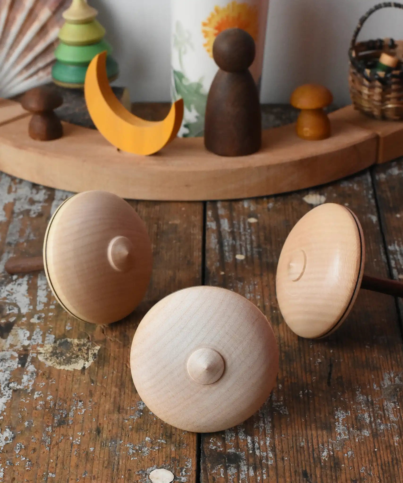 Bottom of three Mader Kreiselmanufaktur bonbon wooden spinning tops placed on a wooden desk in the Babipur playroom.