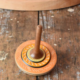 Orange Mader Kreiselmanufaktur bonbon wooden spinning top placed on a wooden desk in the Babipur playroom.
