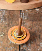 Orange Mader Kreiselmanufaktur bonbon wooden spinning top placed on a wooden desk in the Babipur playroom.
