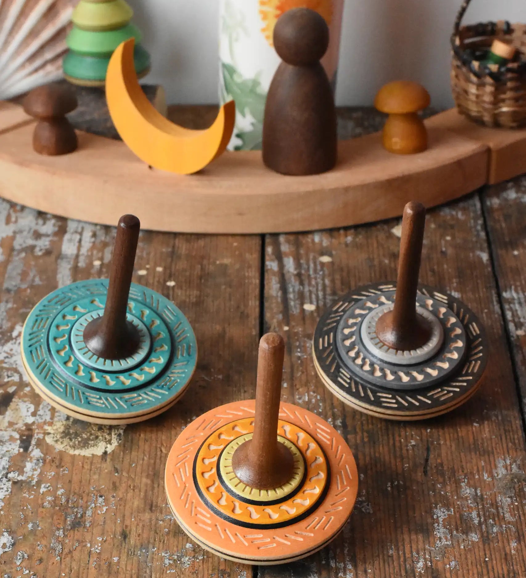 Three Mader Kreiselmanufaktur bonbon wooden spinning tops placed on a wooden desk in the Babipur playroom.