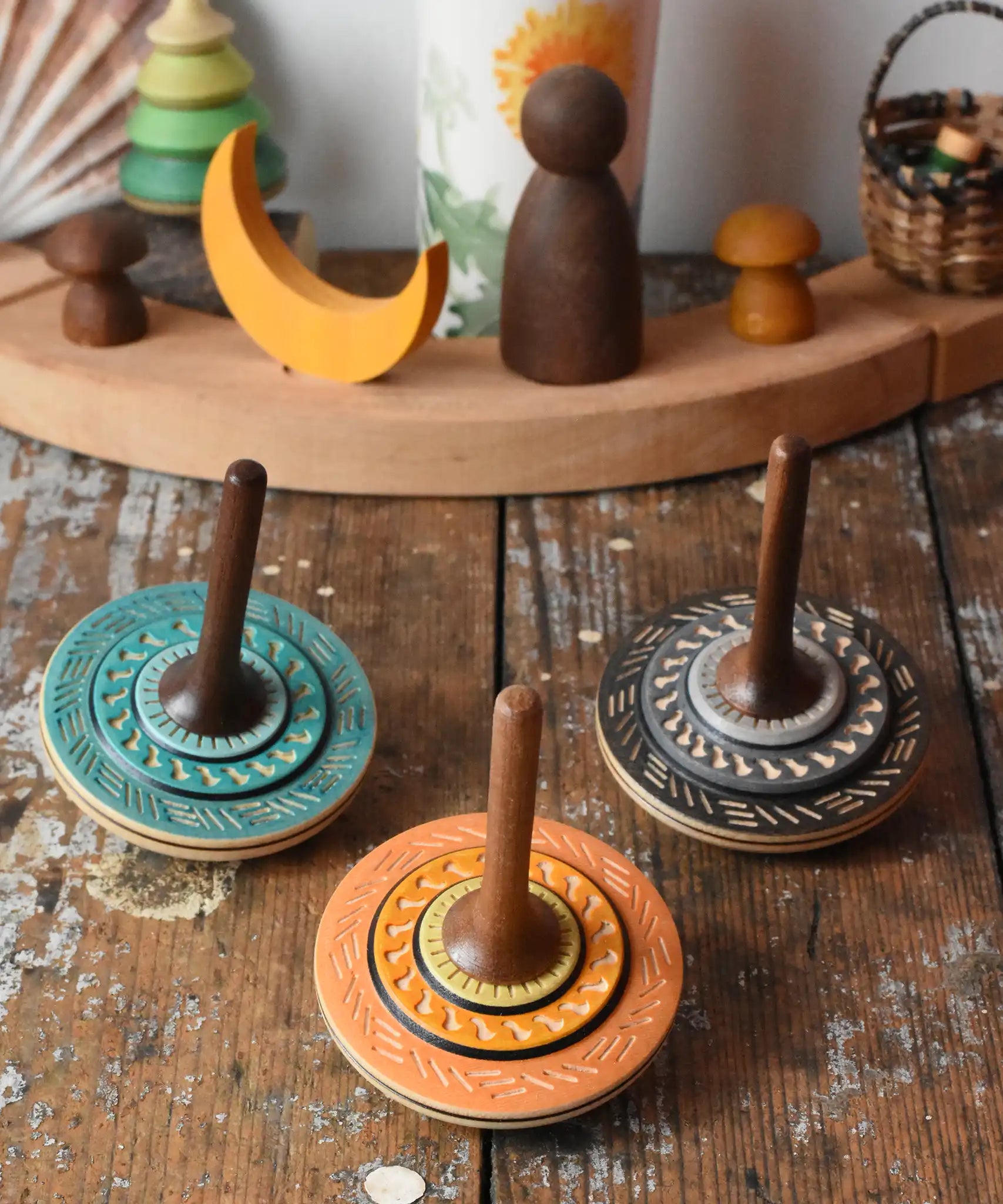 Three Mader Kreiselmanufaktur bonbon wooden spinning tops placed on a wooden desk in the Babipur playroom.