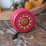 Mader burlesk wooden yoyo in pink 
placed on a wooden surface in the Babipur playroom. 