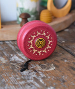 Mader burlesk wooden yoyo in pink 
placed on a wooden surface in the Babipur playroom. 