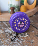 Mader burlesk wooden yoyo in purple placed on a wooden surface in the Babipur playroom. 