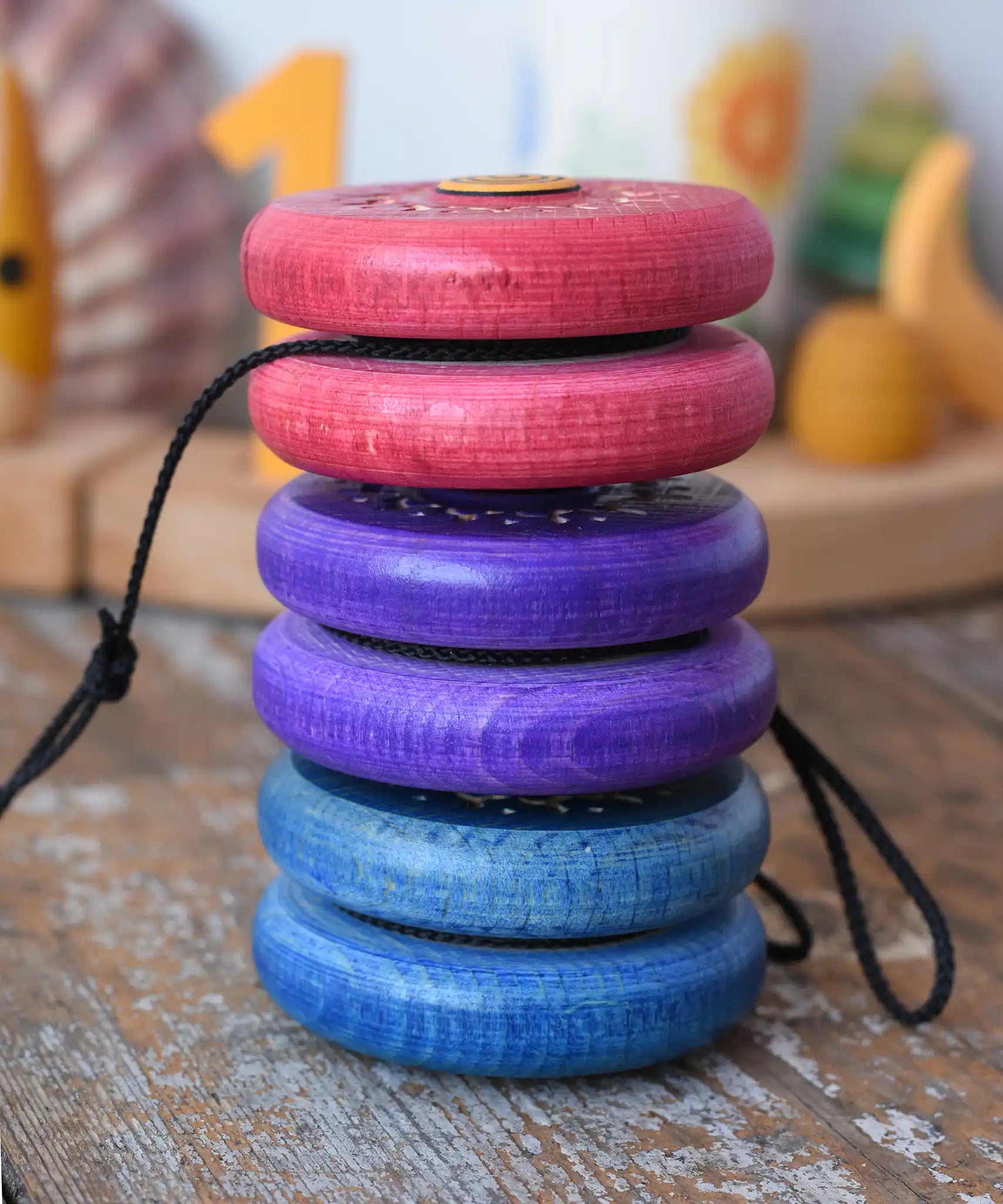 Stack of three Mader burlesk wooden yoyos placed on a wooden surface in the Babipur playroom.