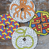 Mader patterned and coloured cardboard discs for 'So And So' Spinning Top placed on a wooden surface in the Babipur playroom. 