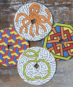 Mader patterned and coloured cardboard discs for 'So And So' Spinning Top placed on a wooden surface in the Babipur playroom. 