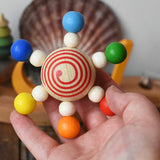 Mader carousel wooden baby grapsing toy with rainbow beads in an adult's hand.