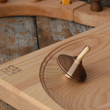 Mader Charlie finger spinning top placed on an ash spinning plate in the Babipur playroom.