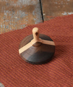 Mader Charlie finger spinning top placed on a piece of cloth on a desk in the Babipur playroom.