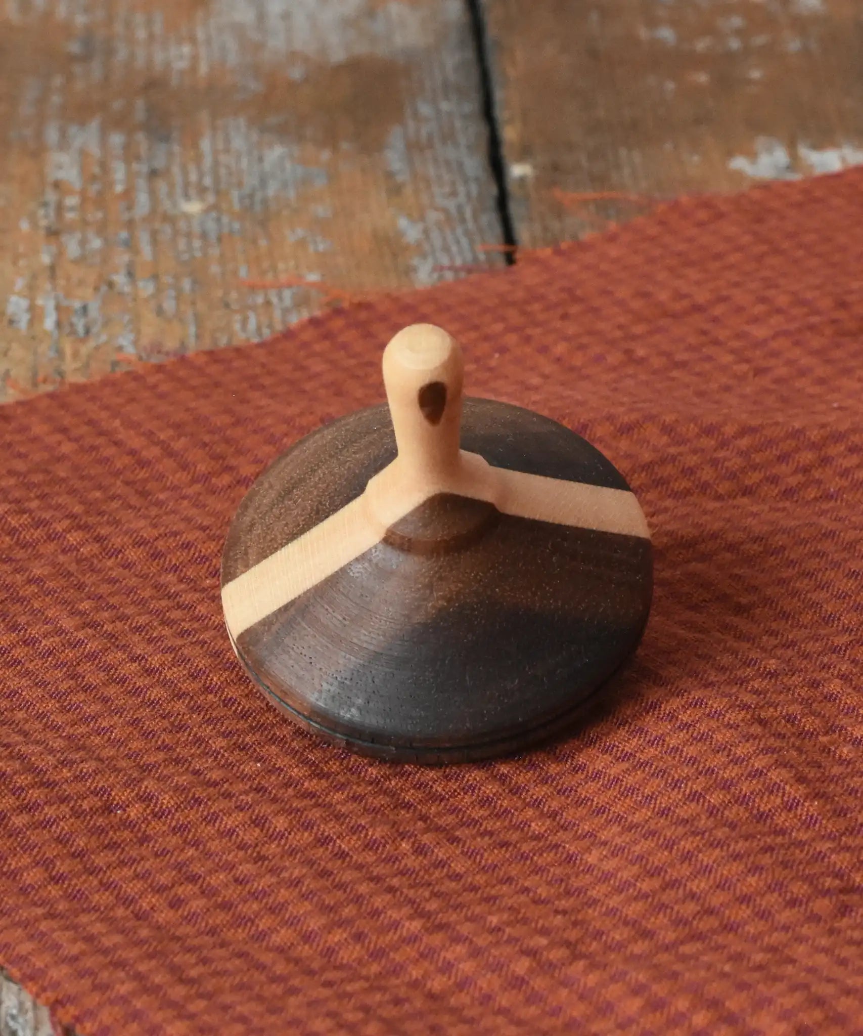 Mader Charlie finger spinning top placed on a piece of cloth on a desk in the Babipur playroom.