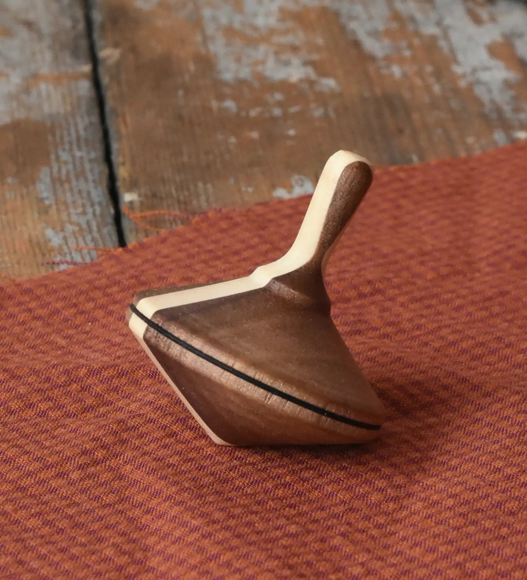 Mader Charlie finger spinning top placed on a piece of cloth on a desk in the Babipur playroom.