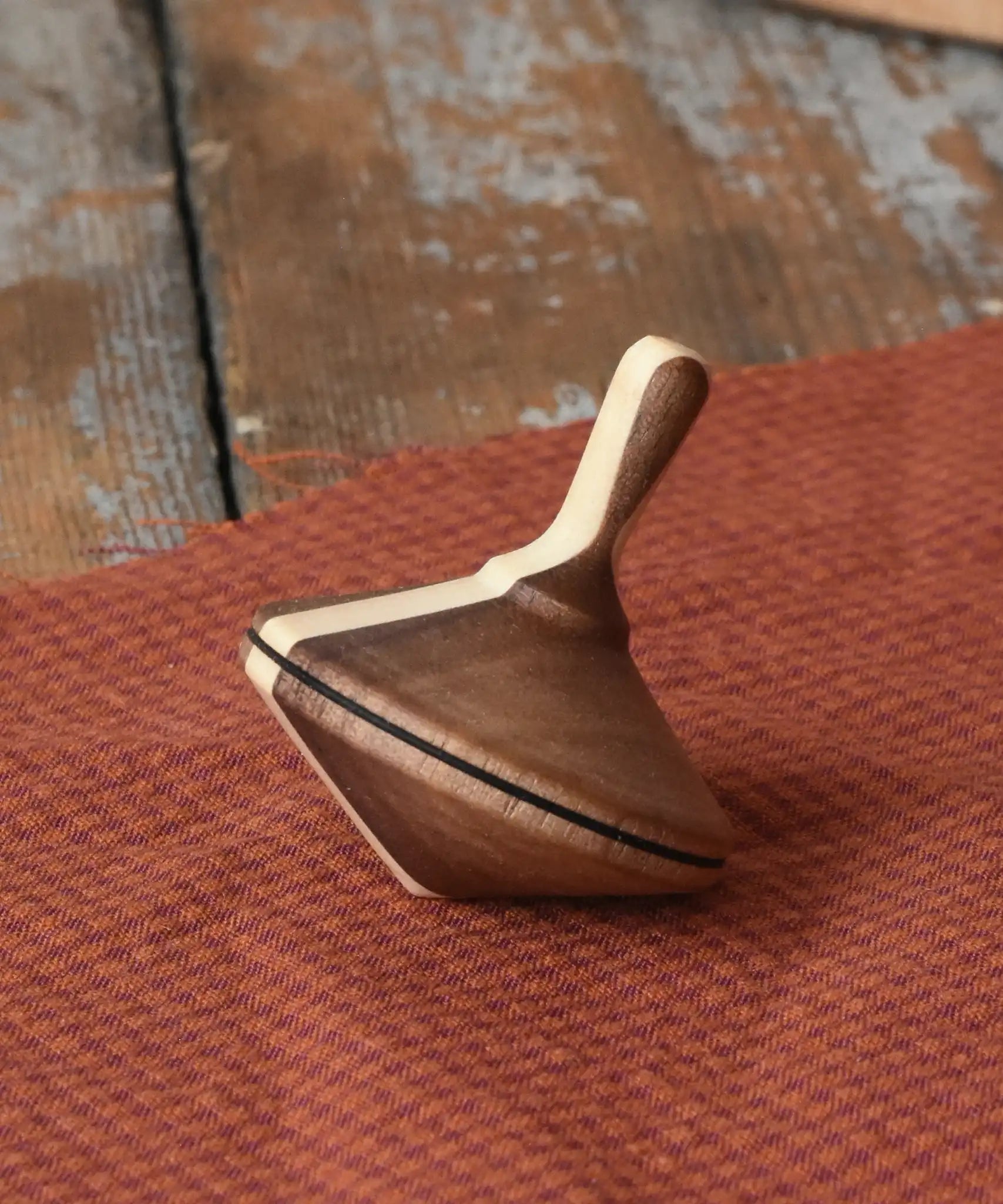 Mader Charlie finger spinning top placed on a piece of cloth on a desk in the Babipur playroom.